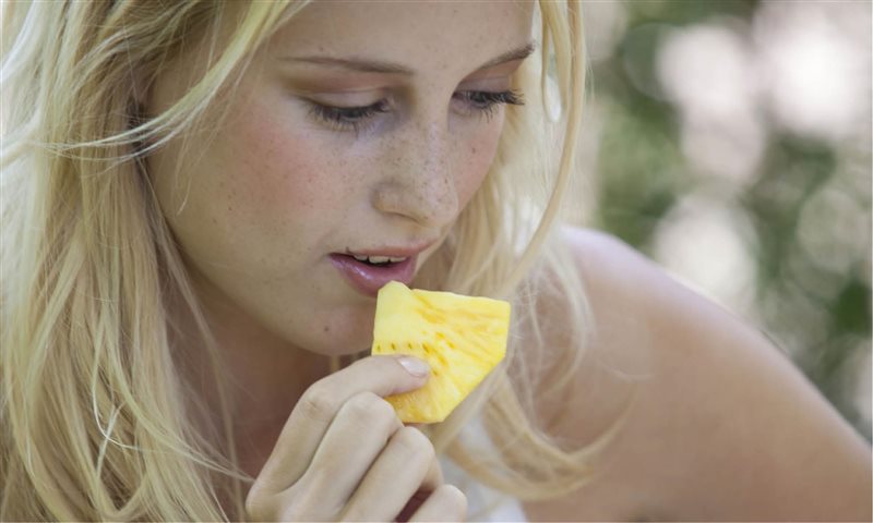 mujer comiendo piña natural
