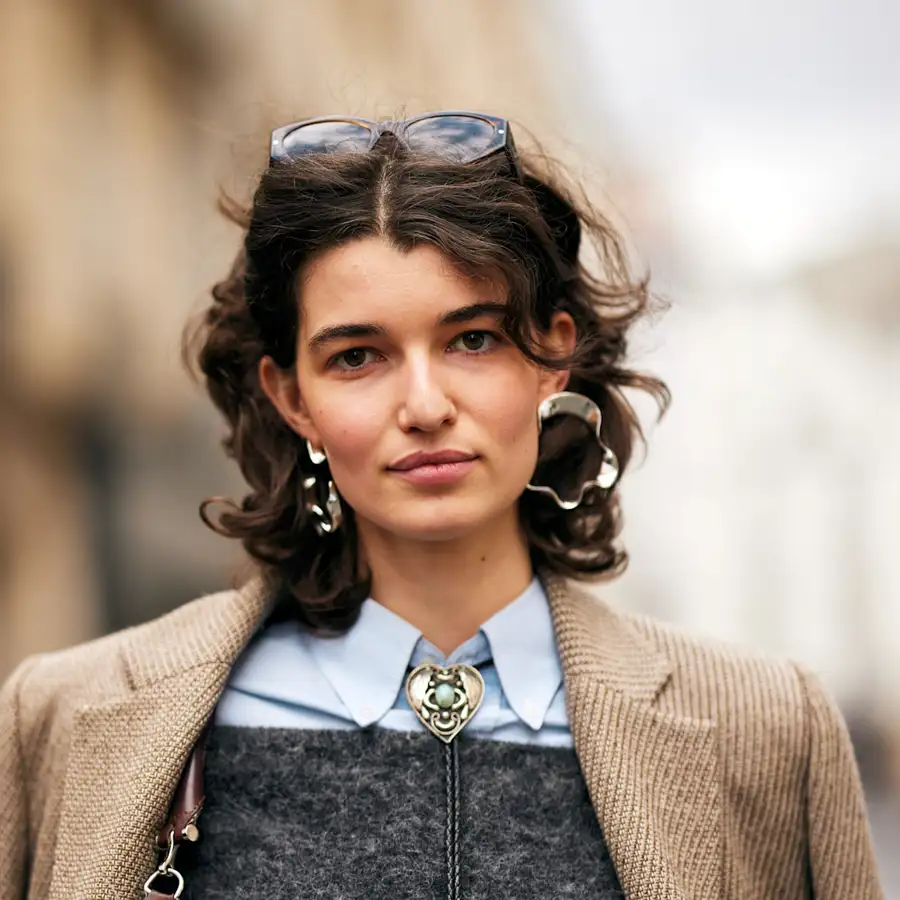 Una mujer 50+ rejuvenece con el corte shaggy curly para cara redonda que da volumen y define el rizo de forma elegante